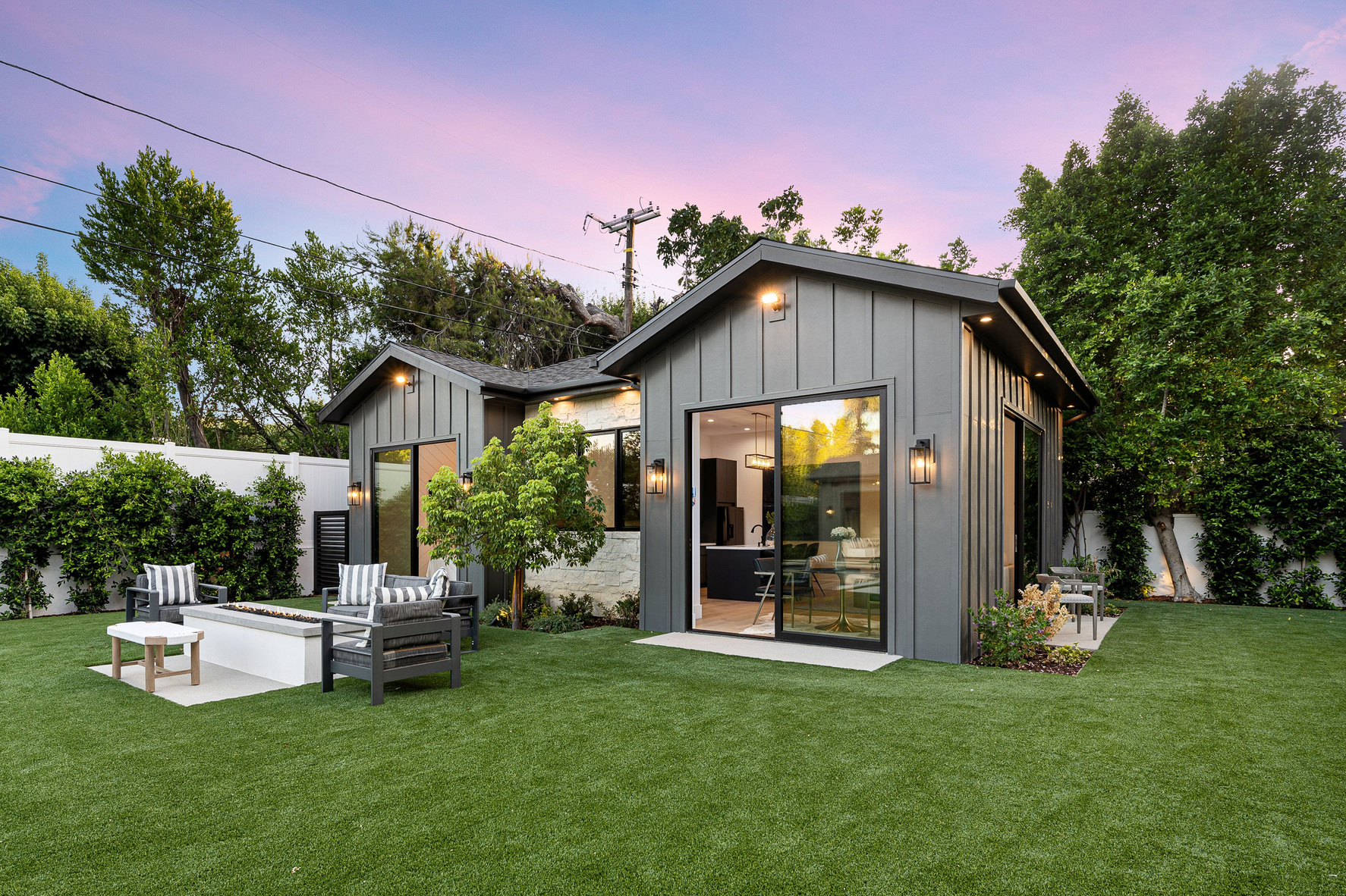 Modern Backyard with small house and patio furniture at sunset.