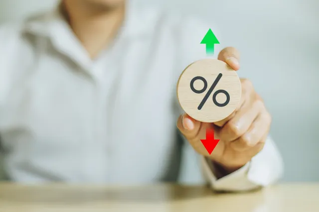A hand holds a disc with a percentage symbol on it, and upward and downward arrows over and below the disc to reflect the rate announcement on September 17, 2025.