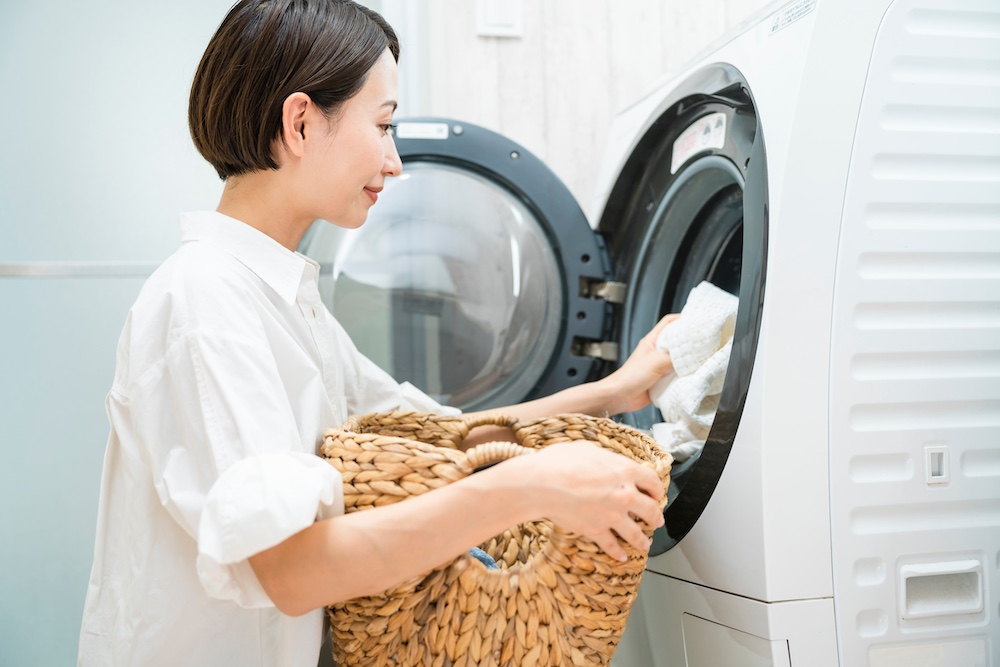 Une femme met du linge dans une machine à laver