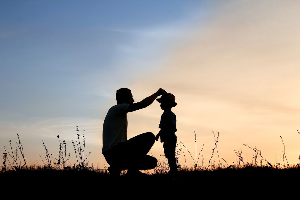 Silhouette d’un père et de son fils heureux jouant au coucher du soleil