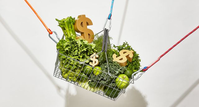 Basket of green-coloured groceries and dollar signs nestled among them